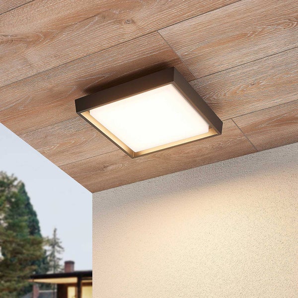 Quadratische LED-Außenleuchte für die Deckenmontage an einer Holzdecke über einer weißen Fassade.