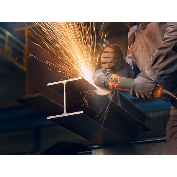 Ein Arbeiter schleift einen Stahlträger mit einem Winkelschleifer, wobei Funken sprühen.