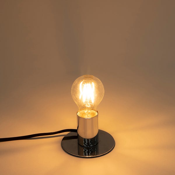 Tischleuchte mit rundem Chromsockel und brennendem LED-Filament-Leuchtmittel.