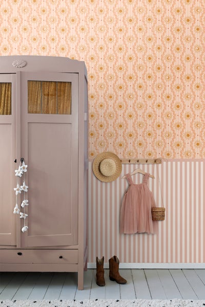Kinderzimmer mit Kleiderschrank, Wandtapete mit Sonnen- und Mondmotiven, Hut, Kleid und Stiefeln.