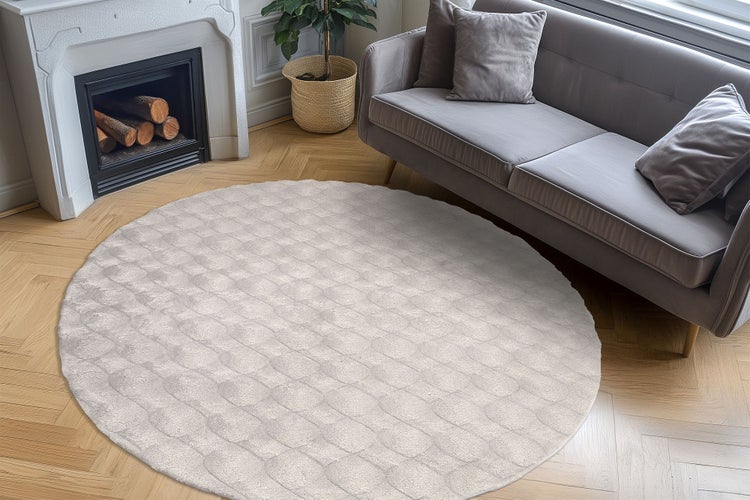 Runder Teppich mit strukturierter Oberfläche in einem elegant eingerichteten Wohnzimmer mit Kamin und Sofa auf Parkettboden.