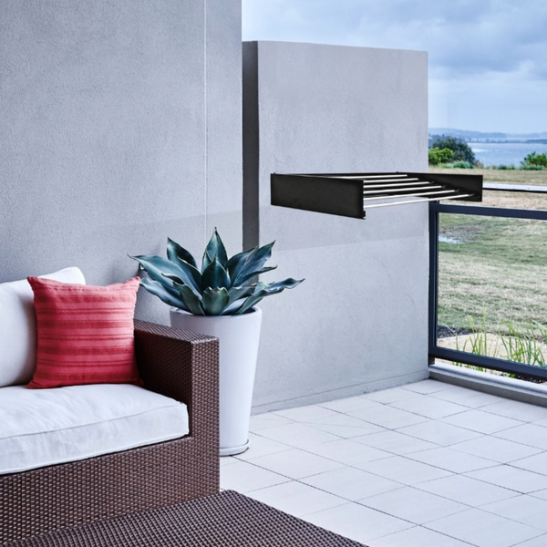 Terrasse mit Rattanmöbeln, Kissen, Pflanze im Topf und Wäscheständer