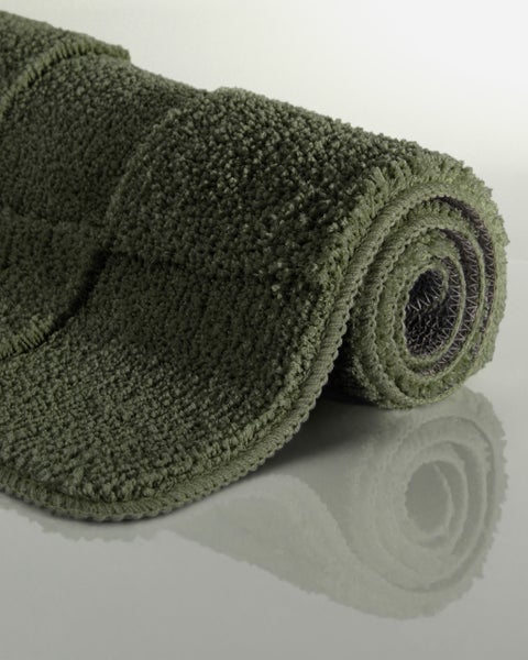 Eingerollte, weiche grüne Badematte mit Hochflor-Struktur.