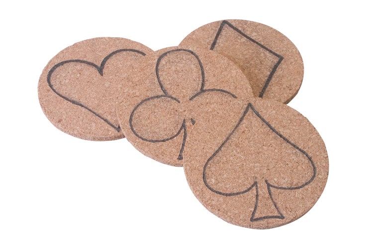 Vier runde Untersetzer aus Kork mit aufgedruckten Spielkartensymbolen wie Herz, Karo, Kreuz und Pik.