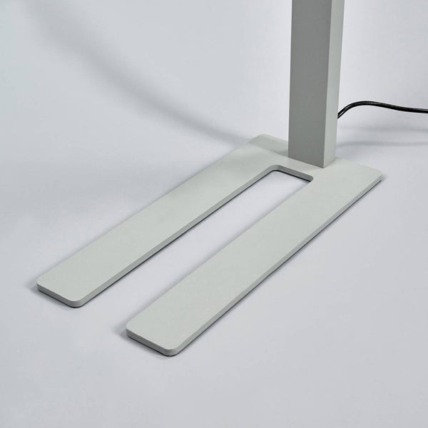 Flacher U-förmiger Standfuß einer Stehleuchte mit vertikaler Säule und Stromkabel.