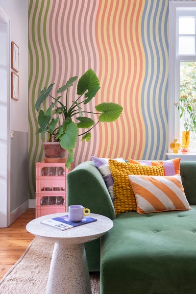 Wohnzimmer mit gemusterter Tapete, Sofa mit Kissen und Beistelltisch