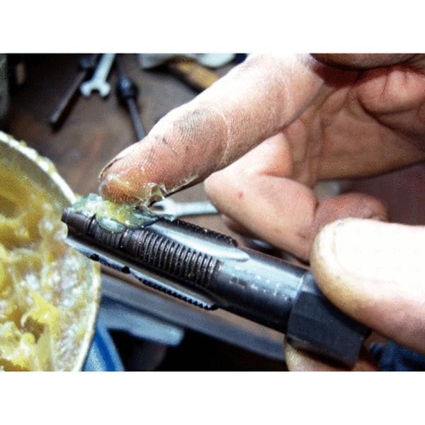 Eine Gewindebohrer wird mit Schmiermittel versehen.