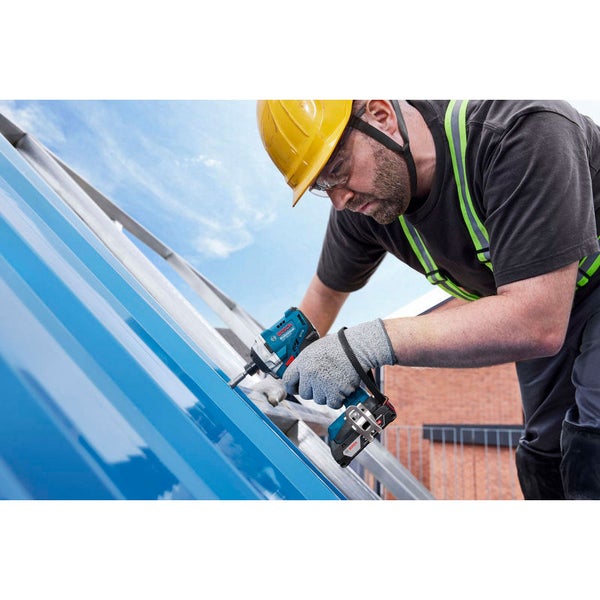 Ein Bauarbeiter befestigt mit einem Akku-Schlagschrauber ein blaues Blech auf einem Dach.