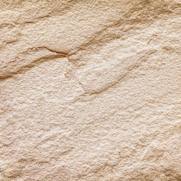 Nahaufnahme einer Natursteinoberfläche mit grober, körniger Textur und ausgeprägten Gesteinsschichten.