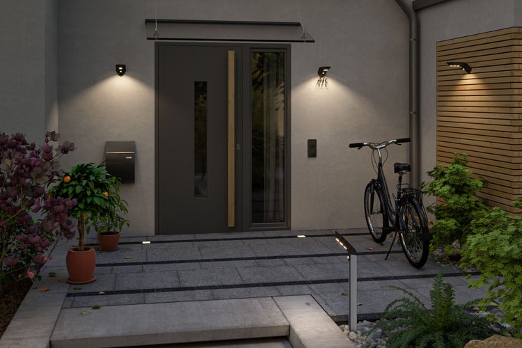 Beleuchteter Eingangsbereich mit Haustür, Wandleuchten und Pflanzen