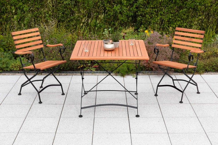 Gartenszene mit Holztisch und zwei Holzstühlen auf einer Terrasse