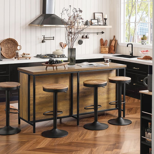 Küchenszene mit Kücheninsel, drei Barhockern und verschiedenen Dekorationsartikeln in einem hellen Raum.