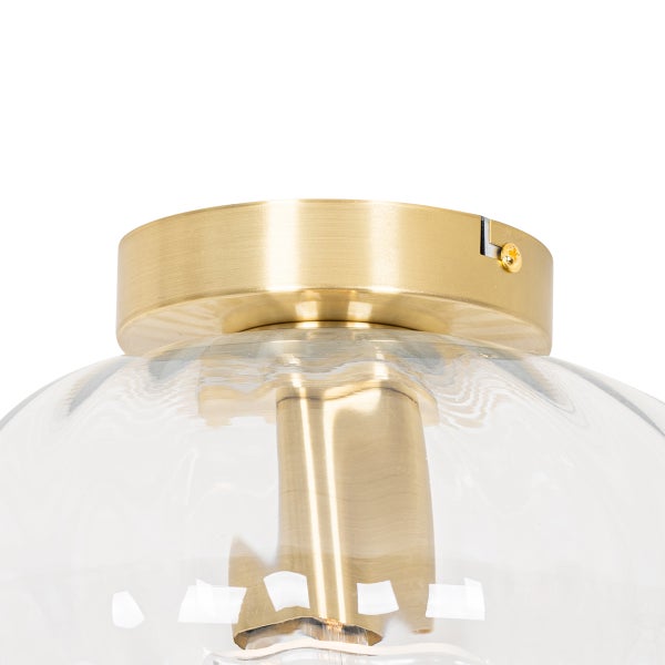 Nahaufnahme einer Deckenleuchte mit einer messingfarbenen Metallbasis und einem klaren Lampenschirm aus Glas.