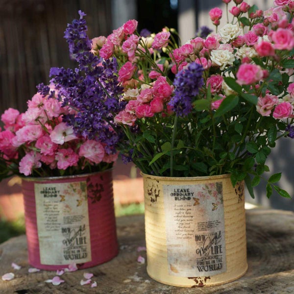 Dekorative Blumenarrangements mit Rosen und Lavendel in verzierten Dosen