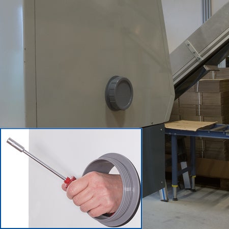 Grauer Revisionsverschluss an einer Industriemaschine, die Detailansicht zeigt eine Hand mit Werkzeug in der kreisförmigen Serviceöffnung.