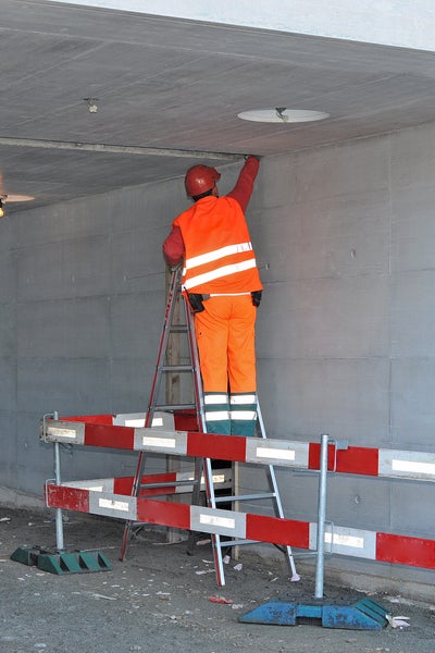 Bauarbeiter auf Leiter bei Inspektionsarbeiten an der Decke