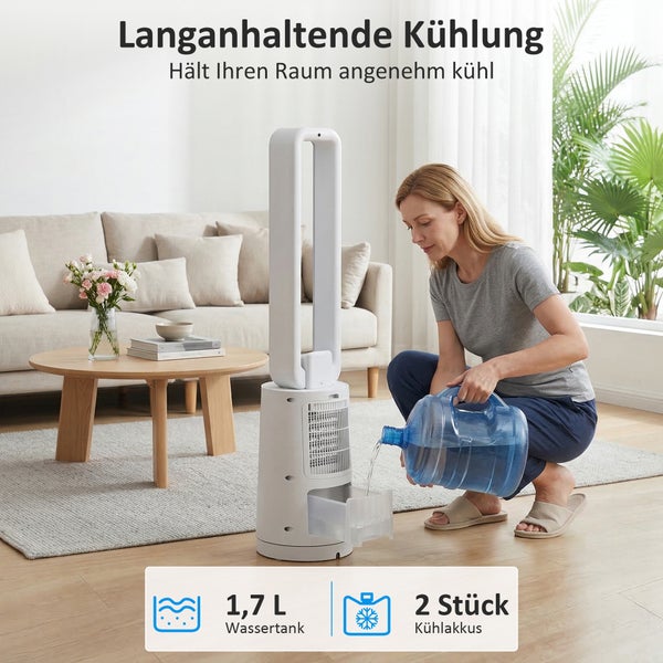 Eine Frau füllt Wasser in den 1,7 Liter Wassertank eines weißen Turmventilators in einem hellen Wohnzimmer mit Sofa und Holztisch.