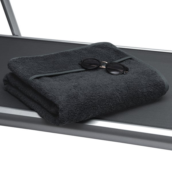 Graues Handtuch und Sonnenbrille auf einer Liege