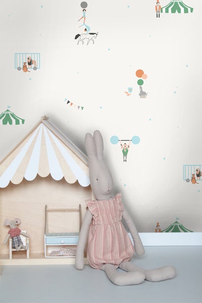Vliestapete mit Zirkusmotiven in einem Kinderzimmer mit Holzspielhaus und großem Stoffhasen.