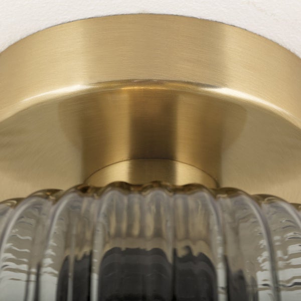 Detailaufnahme einer Deckenleuchte mit goldenem Metallsockel und geriffeltem Glasschirm