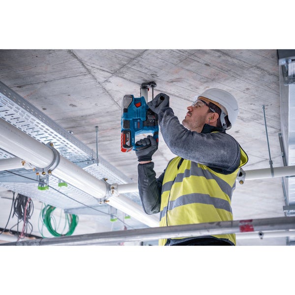 Handwerker befestigt eine Befestigung mit einem Akku-Bohrhammer an einer Betondecke.