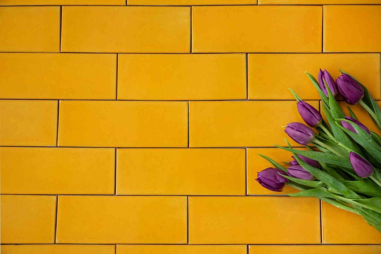 Gelbe rechteckige Wandfliesen mit glatter Oberfläche in Ziegeloptik, dekoriert mit Tulpen.