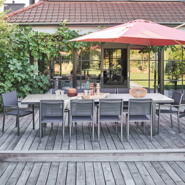 Modernes Gartenmöbel-Set bestehend aus einem großen Esstisch und sechs grauen Textilen-Stühlen auf einer Holzterrasse unter einem Sonnenschirm.