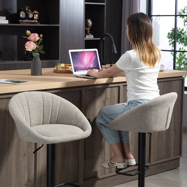 Frau arbeitet am Laptop an einer Kücheninsel mit zwei modernen gepolsterten Barhockern mit Stoffbezug und Metallfuss in hellem Raum.