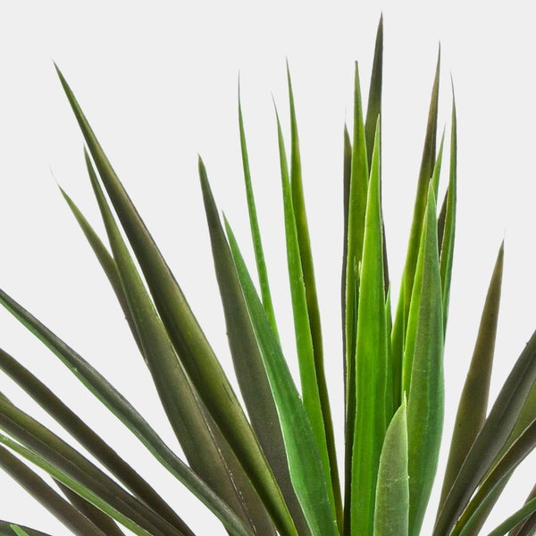 Detailansicht vom strukturierten Stamm einer künstlichen Palme im schwarzen Kunststofftopf mit Erde.