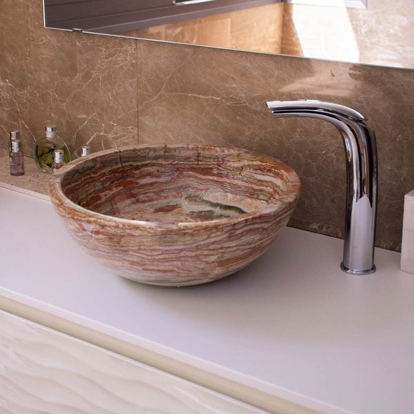 Modernes, helles Badezimmer mit rundem Aufsatzwaschbecken aus Naturstein und geschwungener Chromarmatur auf einem Waschtisch mit Marmorfliesen.