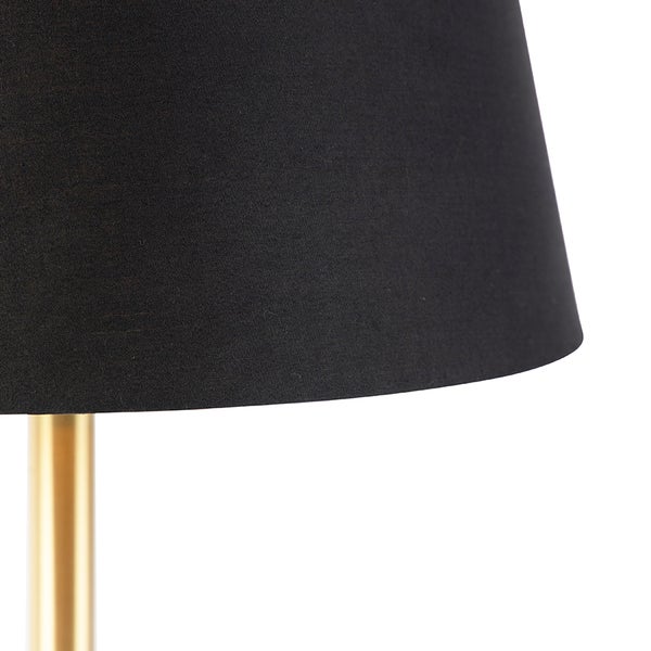 Nahaufnahme eines schwarzen Textilschirms auf einem goldfarbenen Lampenfuß aus Metall.