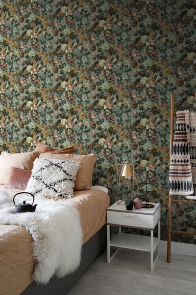 Schlafzimmer mit floraler Tapete, Bett, Nachttisch und dekorativen Elementen.