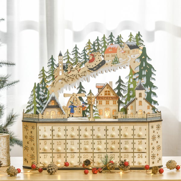 Hölzerner Adventskalender mit 24 Schubladen und einer hell beleuchteten Winterszene aus Holz mit Häusern, Kirche und Weihnachtsmannschlitten.