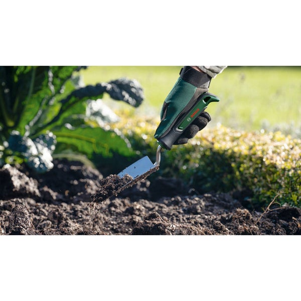 Gärtner mit Handschuhen und Gartenschaufel bei der Gartenarbeit.