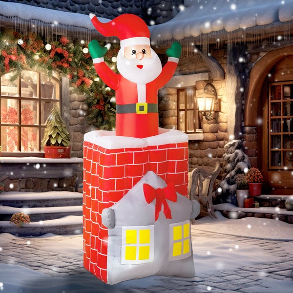 Aufblasbarer Weihnachtsmann im Schornstein mit beleuchtetem Haus und Schleife vor verschneiter Kulisse.