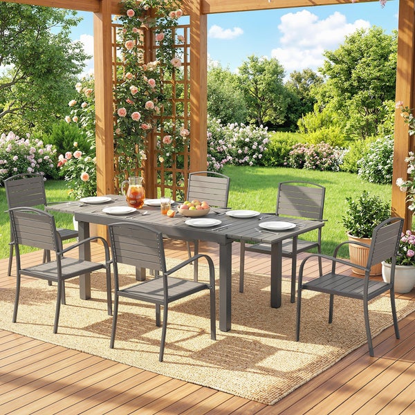 Garten-Essgruppe mit rechteckigem Tisch und sechs Stühlen aus Metall auf einer Holzterrasse unter einer Pergola.