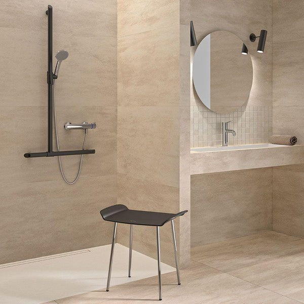 Modernes Badezimmer mit ebenerdiger Dusche, Duschsitz, Waschtisch mit rundem Spiegel und beige gefliesten Wänden in wohnlichem Ambiente.