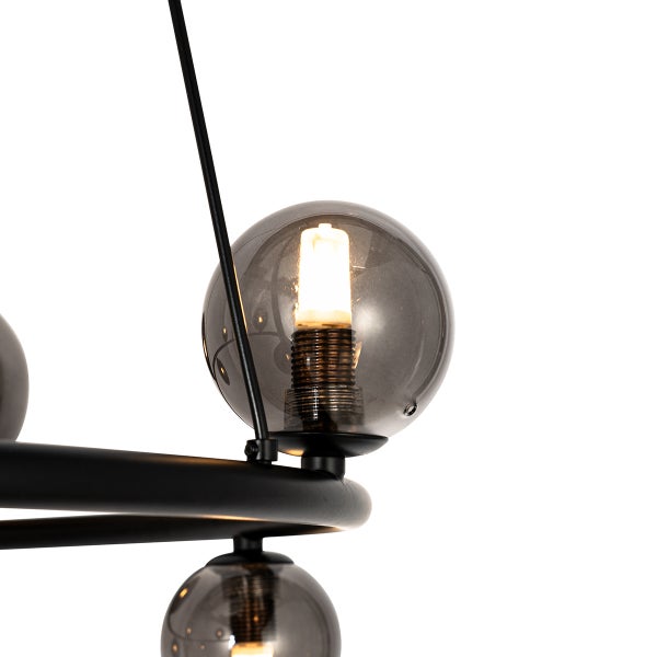 Detailaufnahme einer Pendelleuchte mit runden, rauchfarbenen Glasschirmen und einem schwarzen Metallrahmen.