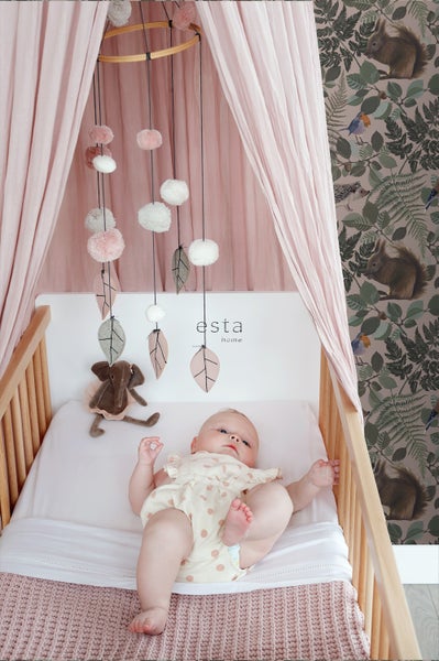 Baby liegt in einem Kinderbett mit Mobile und Baldachin