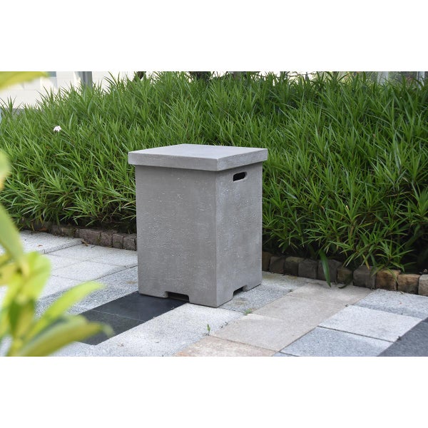 Gasflaschenverkleidung in Beton-Optik im Garten auf einem gepflasterten Weg vor grünen Ziergräsern.
