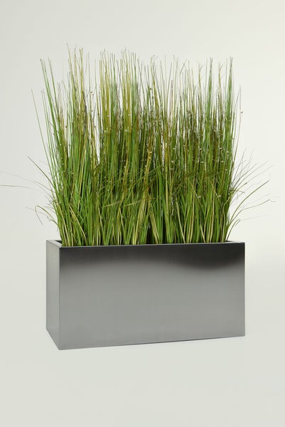 Künstliches Gras in einem rechteckigen Pflanzgefäß aus silberfarbenem Metall.