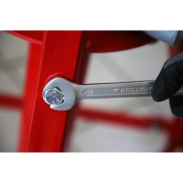 Ein Maulschlüssel der Größe 18 wird verwendet, um eine Schraube an einem roten Objekt festzuziehen.