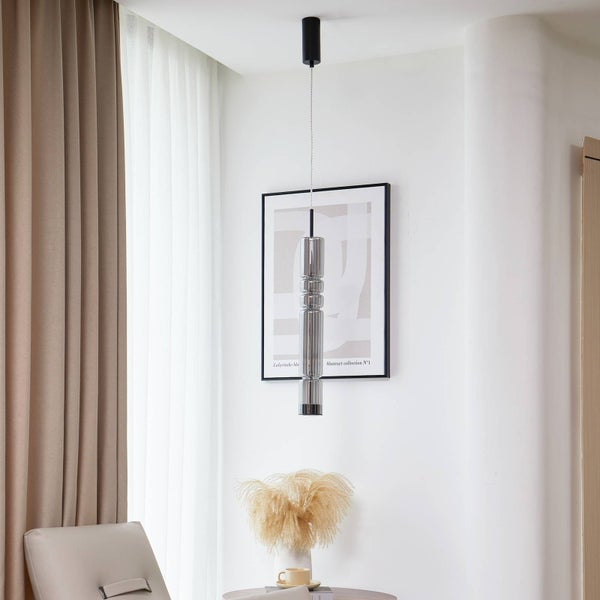 Schlanke Pendelleuchte mit geriffeltem Glasschirm in einem hellen, modernen Wohnraum mit Vorhängen und Dekoration.