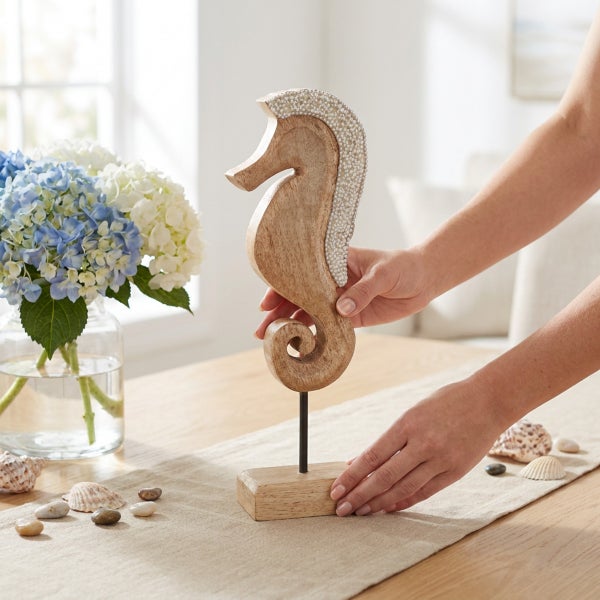 Dekorative Seepferdchen Skulptur aus Holz mit Perlenverzierung auf einem Standfuß zur Tischdekoration.