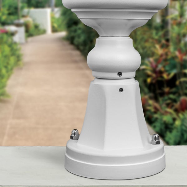 Klassisch geformter weißer Standfuß einer Außenleuchte, montiert auf einem festen Untergrund an einem Gartenweg.