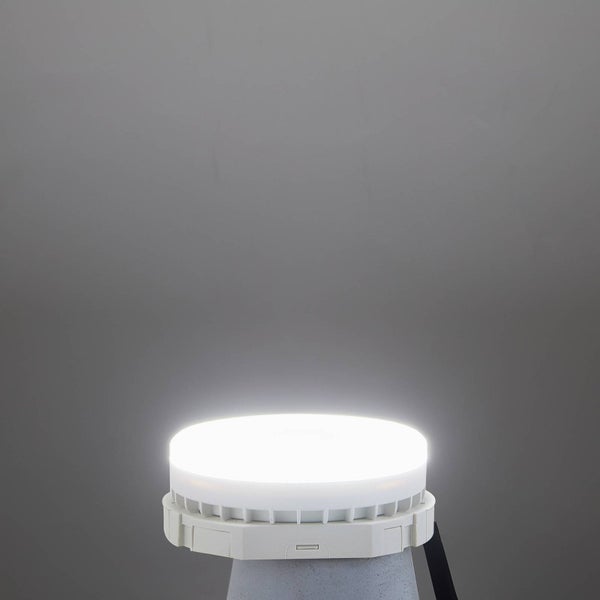 Eingeschaltete runde LED-Arbeitsleuchte mit weißem Kunststoffgehäuse und Kühlrippen an der Unterseite.