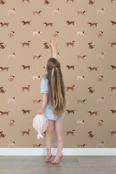 Mädchen steht vor Tapete mit Dackel-Muster