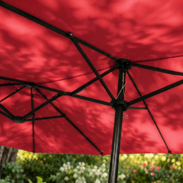 Unteransicht eines roten Sonnenschirms mit schwarzem Metallgestell im Garten.