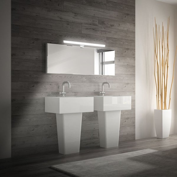 Modernes Badezimmer mit zwei weißen Standwaschbecken, verchromten Armaturen, großem Spiegel und Spiegelleuchte vor einer Wand in Holzoptik.