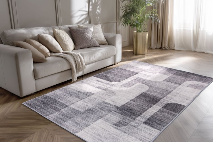 Moderner Wohnzimmerteppich mit abstraktem Muster vor einem Sofa in einem hellen und stilvoll eingerichteten Raum.